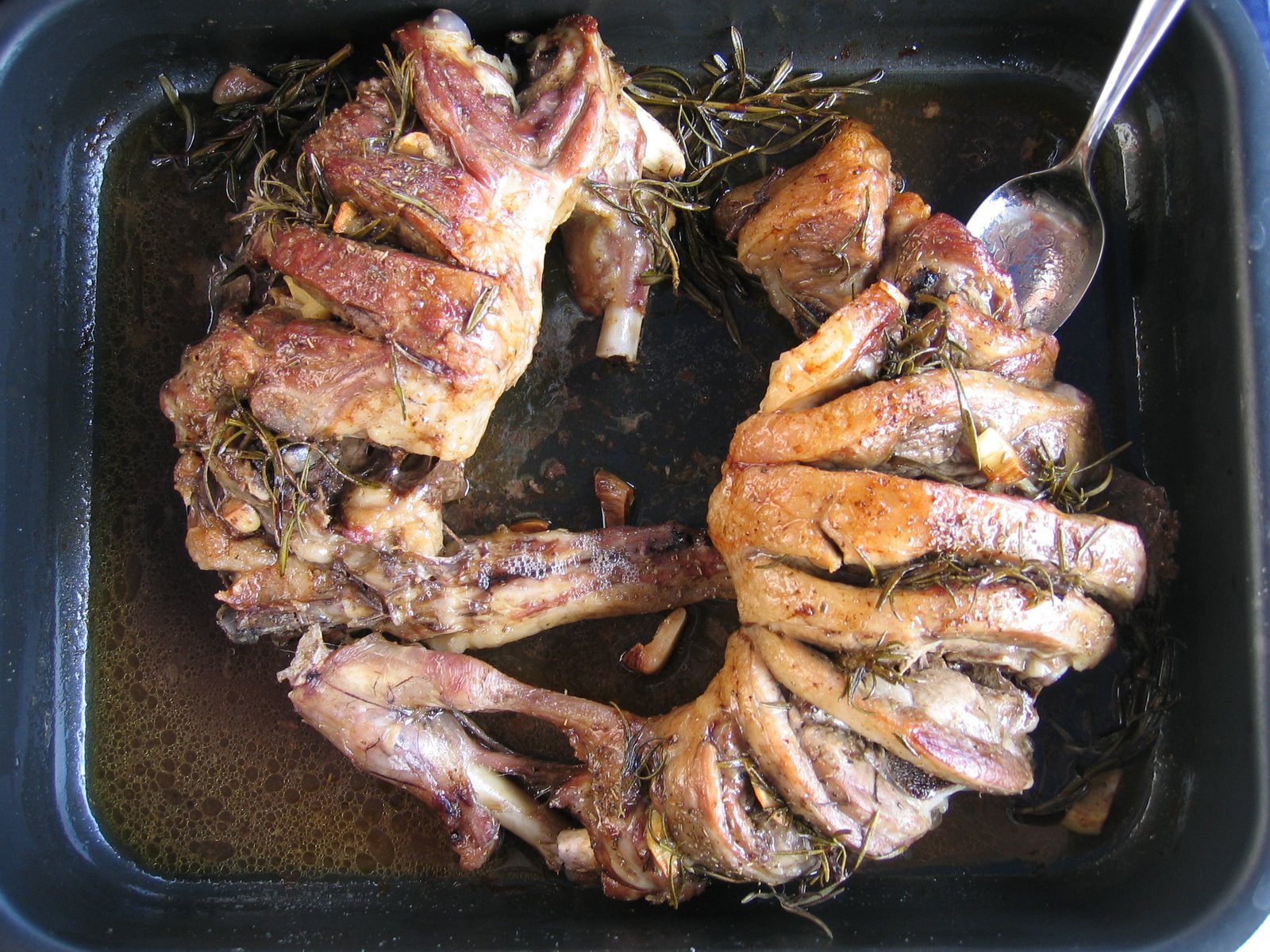 Abbacchio alla romana appena uscito dal forno nella teglia, con rosmarino e aglio