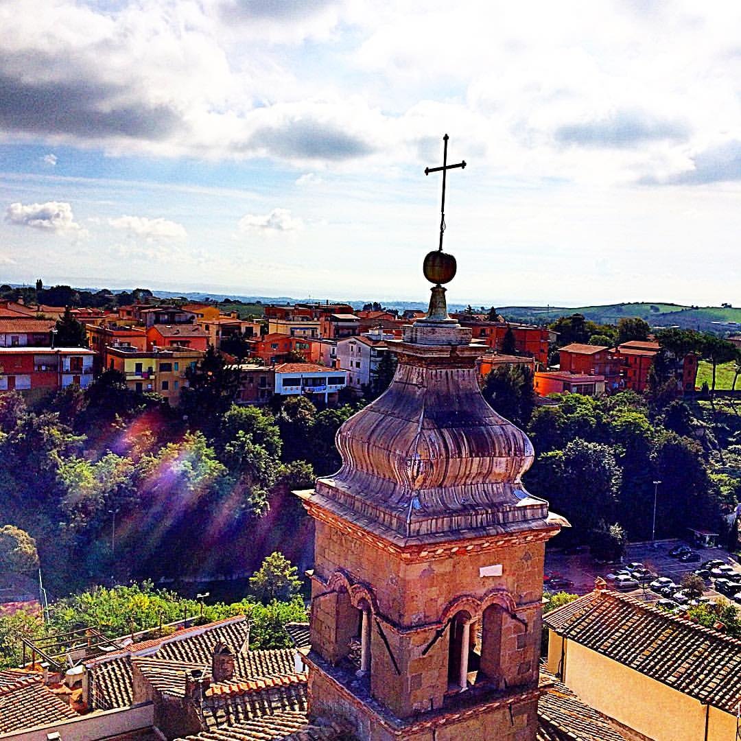 La cuspide del campanile di San Lorenzo sopra i tetti di Formello, con il borgo e la campagna sullo sfondo