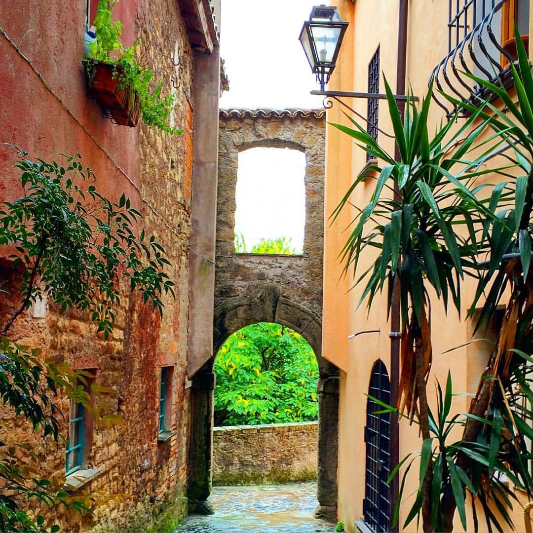 Un vicolo del centro storico di Formello che passa sotto un arco in pietra, tra case color ocra e piante