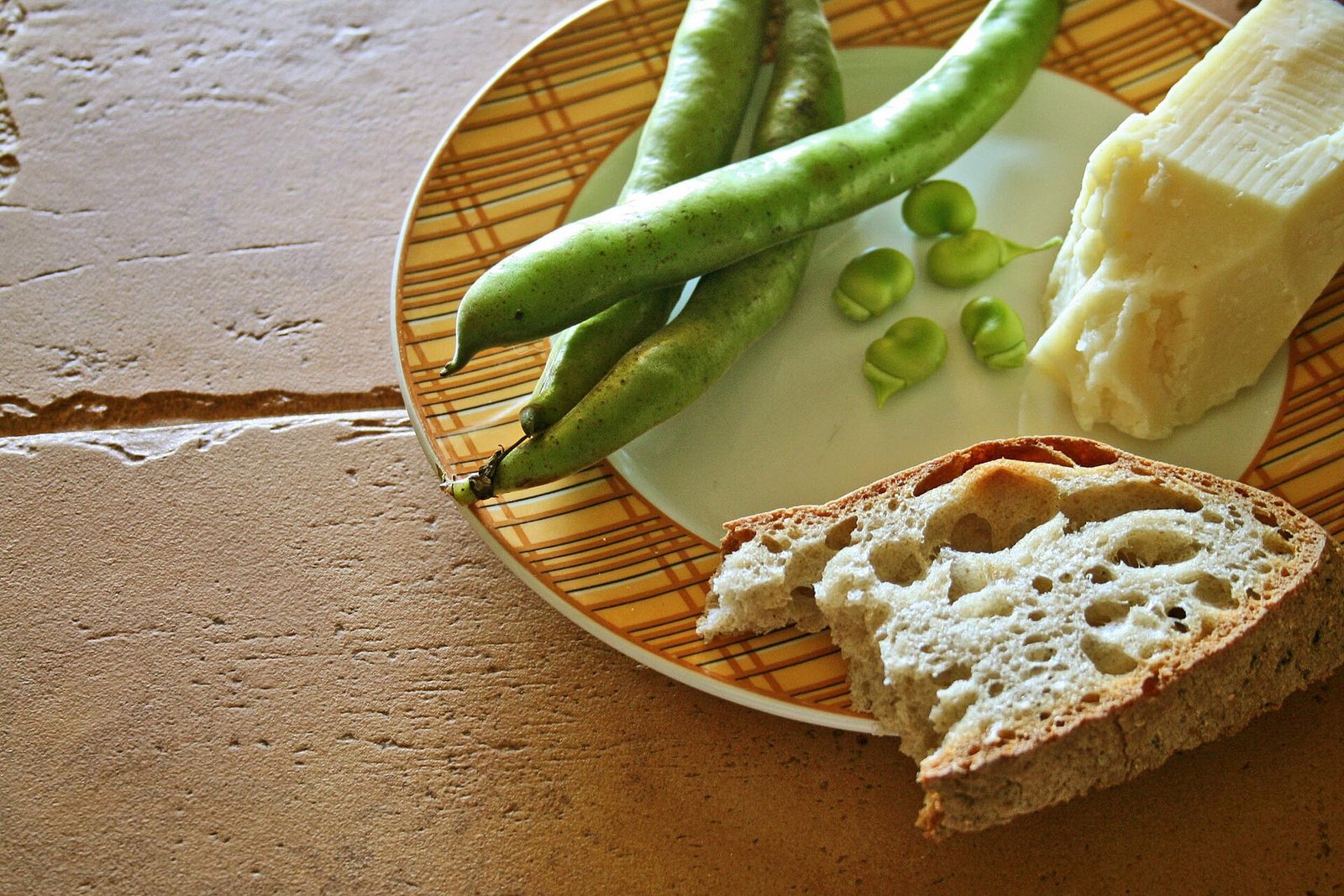 Piatto con scaglie di pecorino romano, fave fresche e una fetta di pane casereccio
